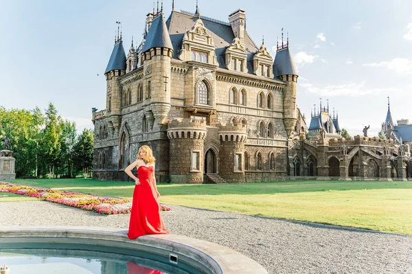 Kırmızı elbiseli bir kadın, Haziran 2019 'da Togliatti' de bir ortaçağ şatosunun arka planında duruyor.