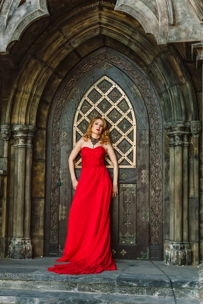 一个穿着红色衣服的女人站在一座中世纪城堡的后面 图库图片