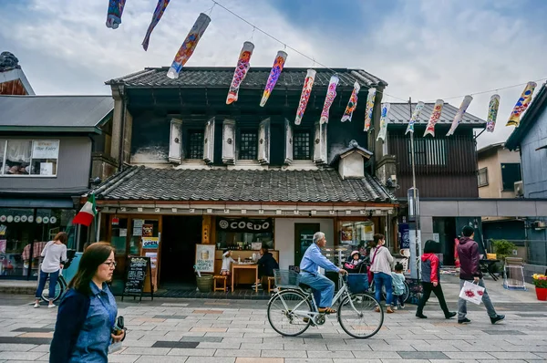 Japan - April 6, 2015: Människor promenad och cykling i gamla staden i Kawagoe med fisk karp windsocks dekoration i The Boy's Festival. Kawagoe, Japan — Stockfoto