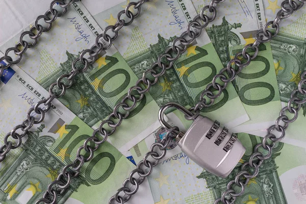 Chains with combination padlock on Euro banknotes as safety bank