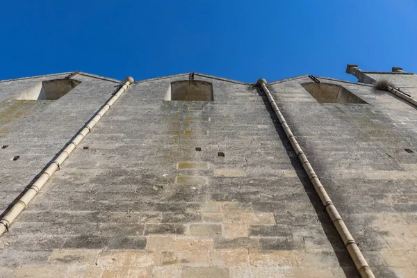 Antigua pared de ladrillo de piedra con canalón y cielo azul claro en el b — Foto de Stock