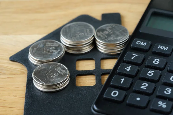 Enfoque suave en pila de monedas en casa de papel con calculadora como p — Foto de Stock