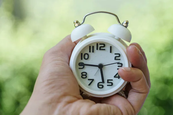 Cerrado de despertador blanco en mano de mujer como negocio o tiempo — Foto de Stock