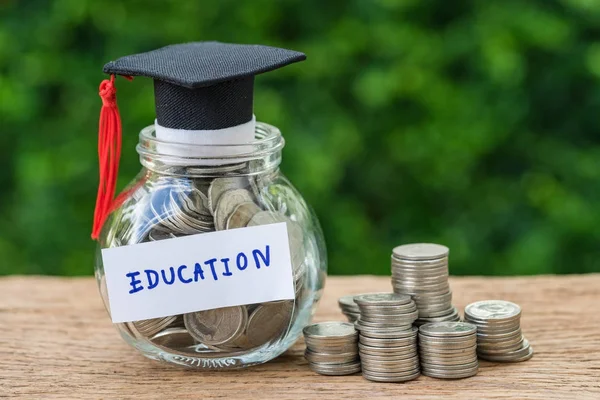 Скляна банка з повним монети і випускників капелюх етикетці як освіту — стокове фото