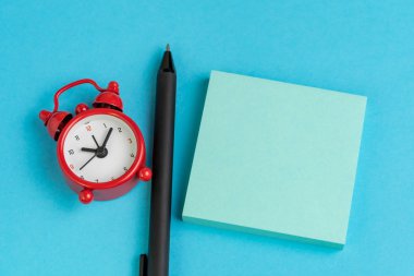 Boş sayfalı mavi kağıt yapışkan not, çalar saat, soli üzerine kalem