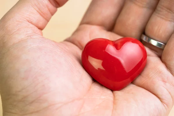 Homme ou femme marié main tenant forme de coeur rouge en utilisant comme amour — Photo