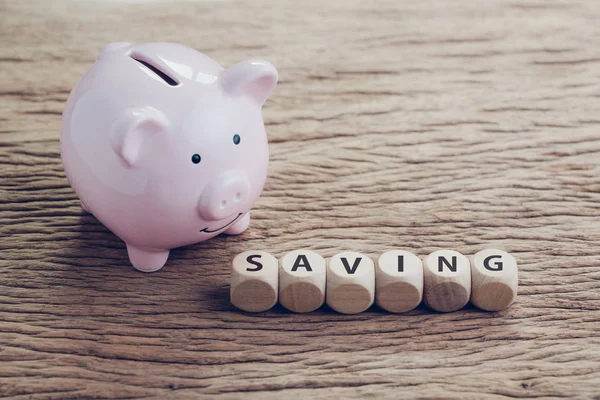 Smiling pink piggy bank or coin bank with wooden cube block with — Stock Photo, Image