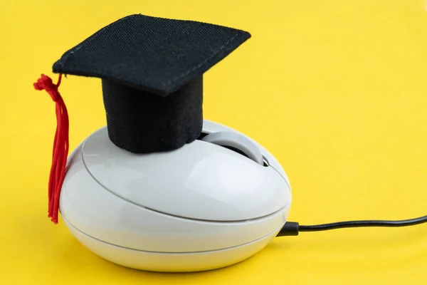 Выпускная шляпа на компьютерной мыши на твердом желтом фоне usin — стоковое фото