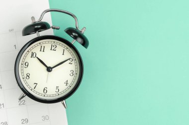 Fotokopi alanı, tatil çizelgesi, iş randevusu için hatırlatma veya iş projesi için son teslim tarihi olan pastel yeşil arka planda siyah alarm saatinin düz görünümü veya üst görünümü.