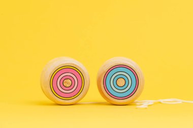 Tahta yoyo ya da yo-yo oyuncağı katı sarı arka planda fotokopi alanı kullanarak yatırım değeri ve yoyo etkisi riskini kullanarak kilo vermeye çalışırken.