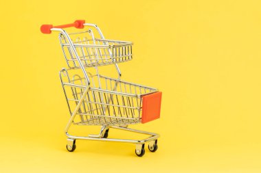 Çevrimiçi alışveriş, e-ticaret, süpermarket tüketici satın alma kavramını kullanarak sarı arka planda çift sepetli alışveriş arabası veya alışveriş arabası.