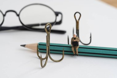 Phishing dolandırıcılığı, hacker saldırısı ve iş güvenliği konsepti, minyatür üzgün iş adamı kalemlerin üzerinde oturmuş not defterine olta atıyor..