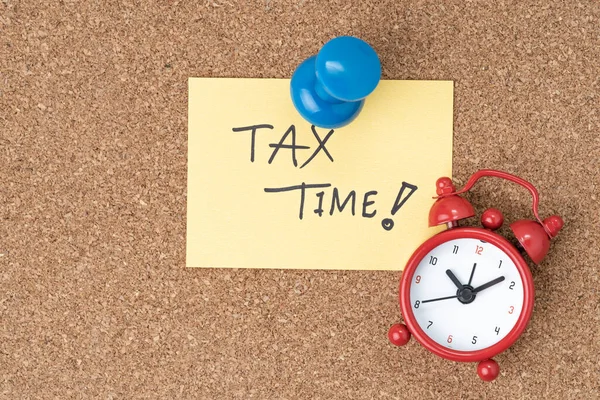 Time to planning for tax or reminder for tax payment concept, Thumbtack pushpin with alarm clock on small paper note written the word Tax Time.
