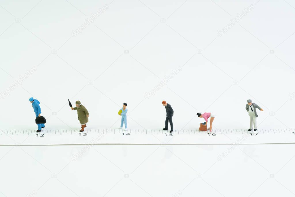 Social distancing, people keep distance in public to protect COVID-19 coronavirus spreading concept, miniature people wait in line keep distance away on measuring tape white background.