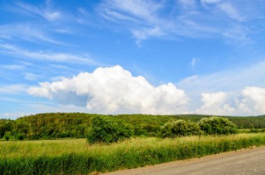 Yeşil çimenli, yollu ve bulutlu yaz manzarası