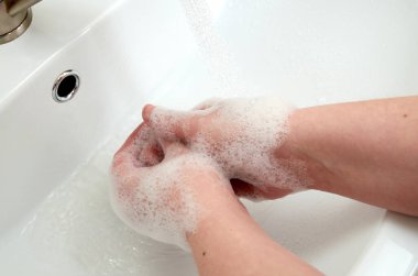 Lavaboda sabunla ellerini yıkıyorsun.