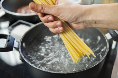 Kaynar suyla birlikte tencerede spagetti pişirmek.