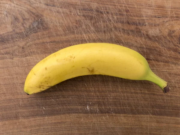 Single banana on wooden cutting board viewed from above — Stock Photo, Image