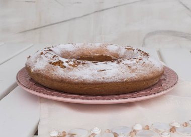 Ciambellone pembe seramik plaka üzerinde pudra şekeri serpilir.