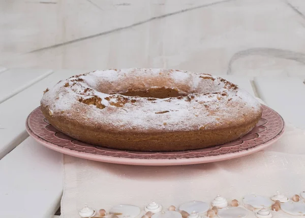 Ciambellone pembe seramik plaka üzerinde pudra şekeri serpilir.