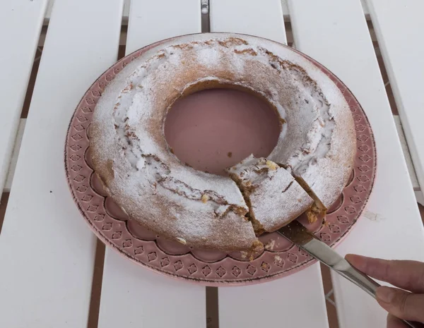 Main avec couteau qui coupe une tranche de ciambellone — Photo