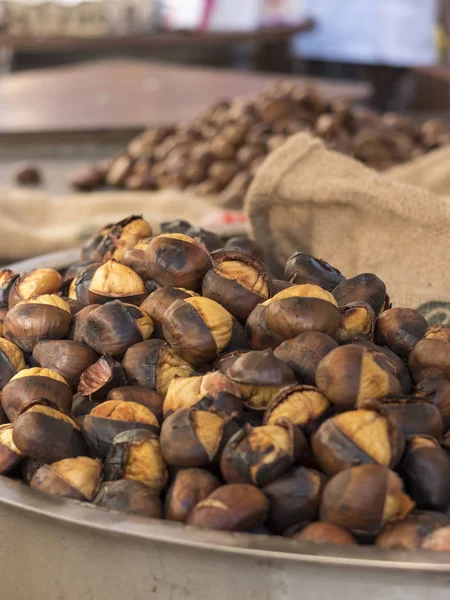 Castanhas assadas cozidas em um caixote com fogo de madeira. Perto de sacos de juta — Fotografia de Stock