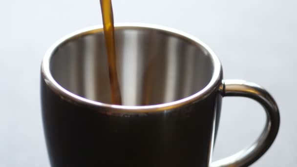 verser du café noir dans une tasse en métal 