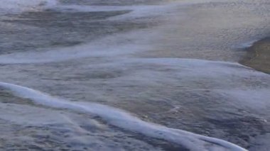 Kumlu bir sahilde yumuşak dalgalar