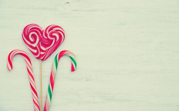 Lollipop in the shape of a heart and candies on a wooden background in vintage style.Place for text. Top view — Stock Photo, Image