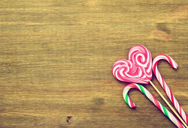 Lollipop in the shape of a heart and candies on a wooden background in vintage style.Place for text. Top view — Stock Photo, Image