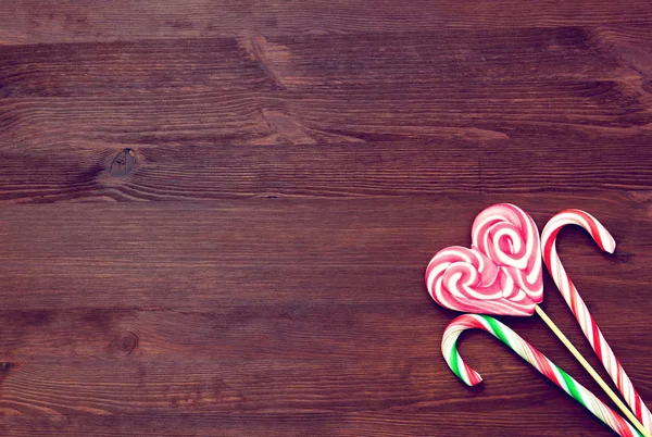 Lollipop i form av ett hjärta och godis på en trä bakgrund i vintagestil. Plats för text. Ovanifrån — Stockfoto