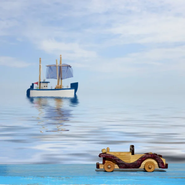 Autíčko na modré dřevěný povrch a toy plachetnice na moři — Stock fotografie