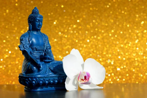 Голубой статуя Будды и цветок орхидеи на ярком золотом блестящем фоне с боке — стоковое фото