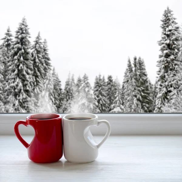Two cups of coffee on a windowsill. In the background, a beautiful winter forest in snow — Stock Photo, Image