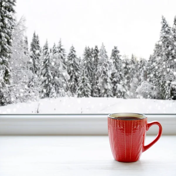 窓枠にコーヒーのカップ。背景には、雪の中で美しい冬の森で — ストック写真
