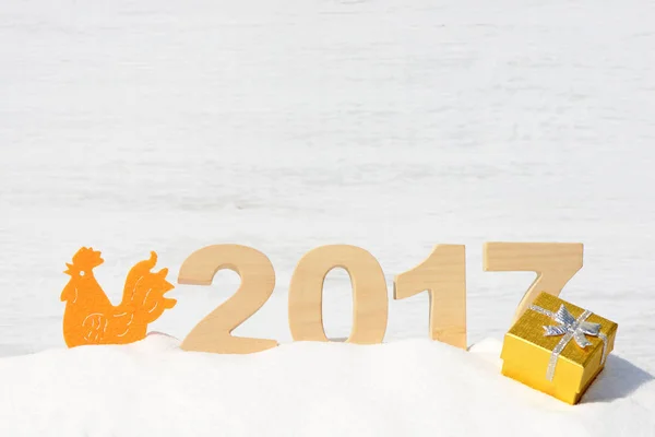 Gallo, símbolo de 2017 en el calendario chino. Gallo y los números 2017 en una deriva de nieve sobre un fondo de madera blanca — Foto de Stock