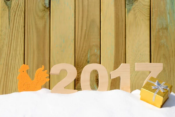 Gallo, símbolo de 2017 en el calendario chino. Gallo y los números 2017 en una deriva de nieve sobre un fondo de madera — Foto de Stock