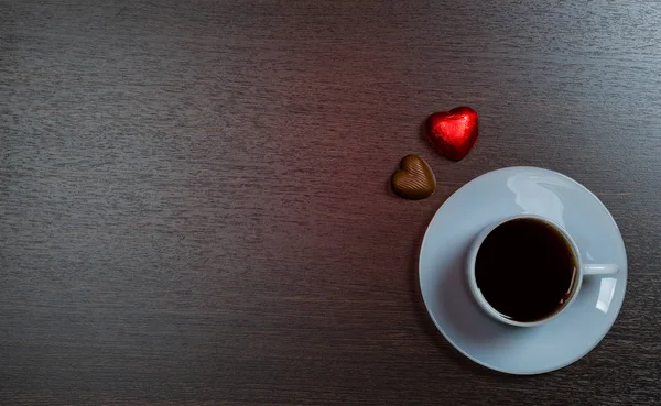 Fondo con taza de café y dulces de chocolate en la oscuridad —  Fotos de Stock