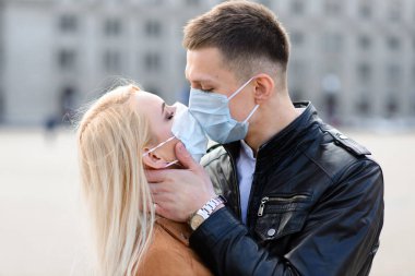Şehir caddesinde maskeli genç bir çift. Tecrit, karantina.