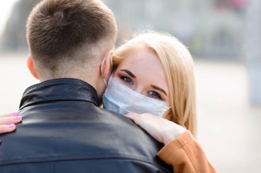 Şehir caddesinde maskeli genç bir çift. Tecrit, karantina.