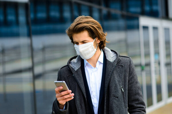 Young man in a medical mask outside looking for a job.