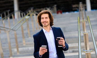 Yakışıklı bir işadamının portresi telefon ve kahve fincanı şehir sokaklarında.