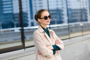 Güneş gözlüklü, telefonlu, laptoplu, sokaklarda kahve içen genç ve güzel bir iş kadını.