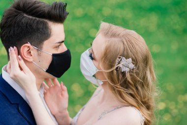 Düğün günlerinde karantina sırasında parkta maske takan genç bir çift. Coronavirus, hastalık, koruma, hastalık. Avrupa kutlamaları iptal edildi.