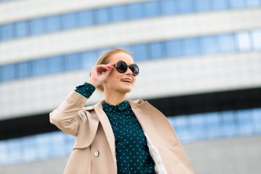 Güneş gözlüklü, telefonlu, laptoplu, sokaklarda kahve içen genç ve güzel bir iş kadını.