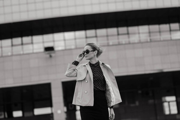 Young beautiful businesswoman with sunglasses, phone, laptop, cup of coffee in the city street