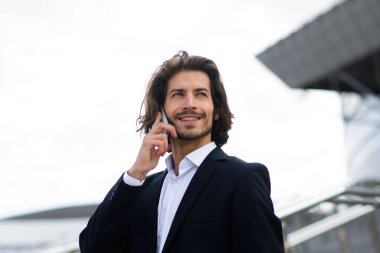 Yakışıklı bir işadamının portresi telefon ve kahve fincanı şehir sokaklarında.