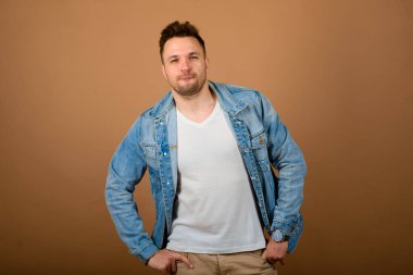 Yakışıklı adam ayakta ve gülümsüyor açık kahverengi stüdyo arka planında izole edilmiş. Yarım boy erkek portresi. İnsan duyguları, yüz ifadesi konsepti..