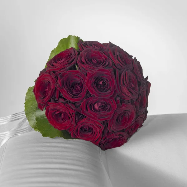 Ein Brautstrauß mit dunkelroten Rosenblüten in hellgrauem Ambiente — Stockfoto