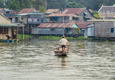 Bir adam küçük tahta teknesiyle Bassac Nehri 'ni geçiyor.